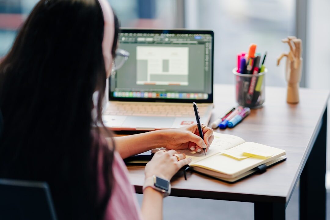 woman writing notes with laptop